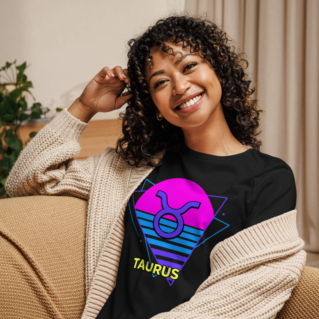 Smiling woman wearing taurus retro 80s astrology shirt with pink sun design while lounging on couch
