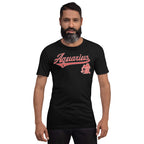 A man wearing a black short-sleeve t-shirt with a pink 'Aquarius' script graphic and mascot on the chest, set against a plain white background.