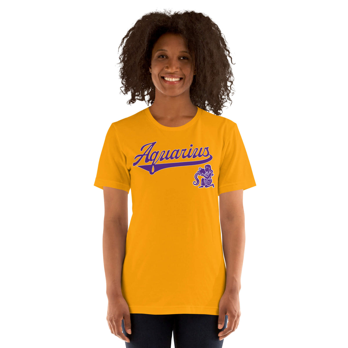 A smiling woman with curly dark hair wearing a gold short-sleeve t-shirt with a purple 'Aquarius' script and zodiac graphic on the chest, set against a plain white background.