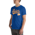 A man wearing a royal blue crewneck t-shirt with a retro-style orange and white 'Aries' graphic on the chest, paired with dark gray jeans, set against a plain white background.