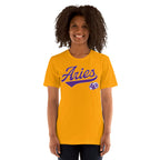 A smiling woman with curly dark hair wearing a gold short-sleeve t-shirt with a purple 'Aries' graphic and a small ram logo on the front, set against a plain white background.