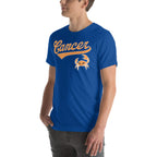 A man wearing a royal blue crewneck t-shirt with a retro-style orange and white 'Cancer' script and crab graphic on the chest, shown against a plain white background.