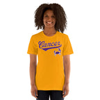 A smiling woman with curly dark hair wearing a bright gold short-sleeve t-shirt with 'Cancer' and a crab graphic printed in purple on the chest, set against a plain white background.