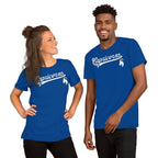 A man and a woman modeling matching royal blue t-shirts with a white 'Capicorns' script and capricorn graphic on the chest, set against a plain white background.