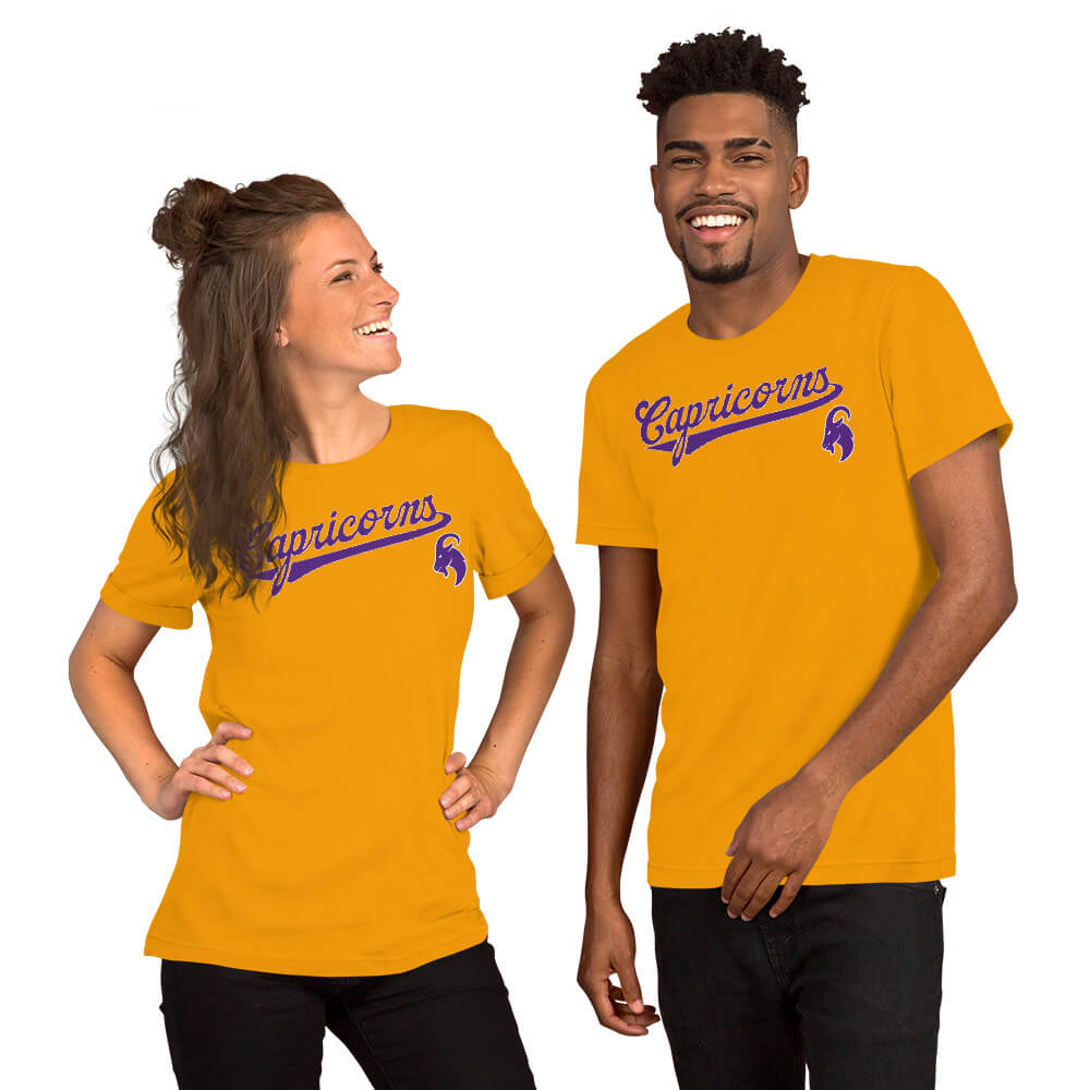 A man and a woman modeling matching gold t-shirts with a purple 'Capricorns' script and a capricorn graphic on the chest, set against a plain white background.