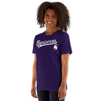 A woman with curly dark hair wearing a purple short-sleeve t-shirt with 'Capricorns' and a white horn emblem printed on the chest, set against a plain white background.
