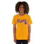 A smiling woman with curly dark hair wearing a bright gold short-sleeve t-shirt with a purple 'Gemini' script and zodiac symbol on the chest, set against a plain white background.