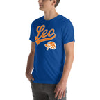 A man wearing a royal blue crewneck t-shirt with a large orange and white 'Leo' script graphic and a lion head mascot logo on the front, set against a plain white background.