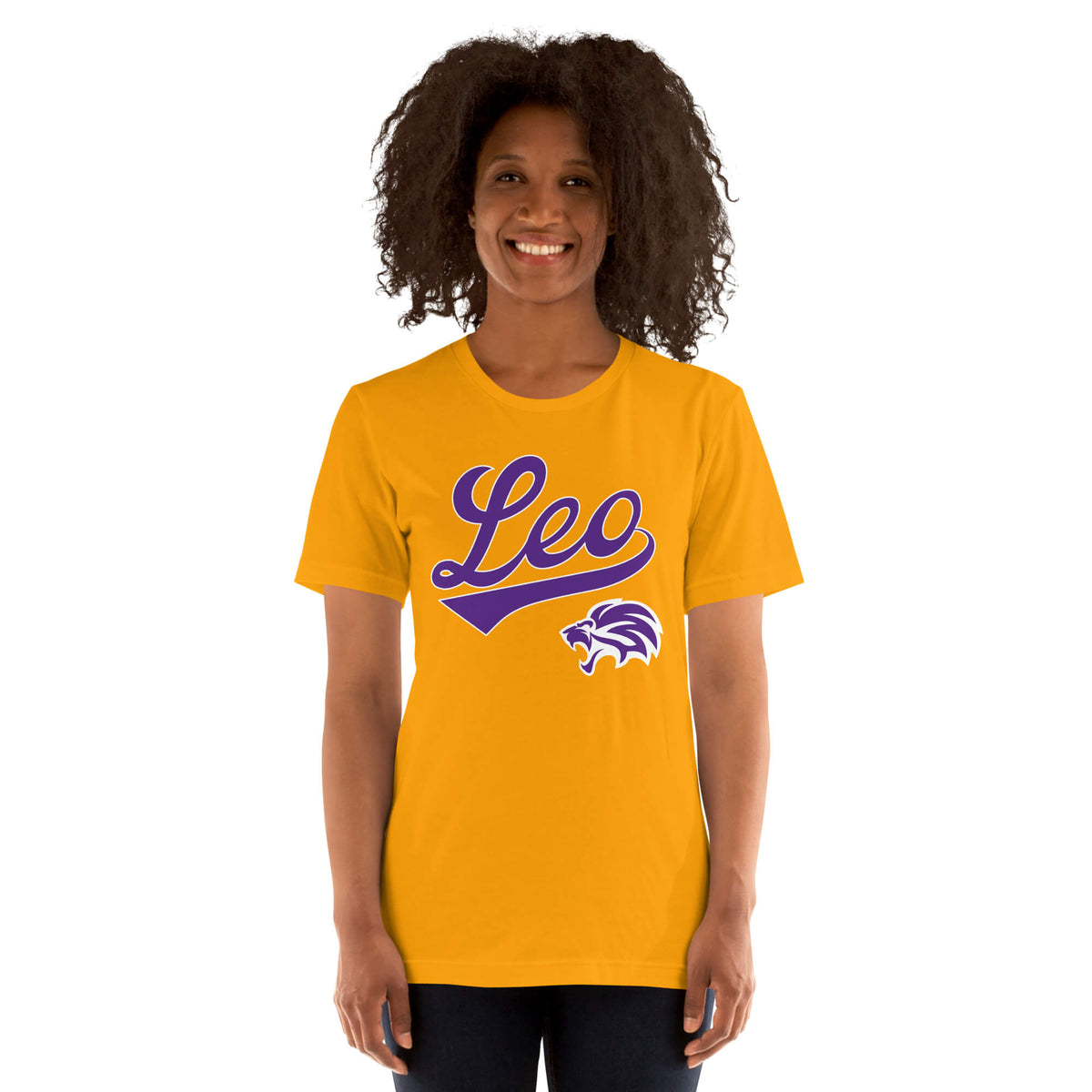 A smiling woman with curly dark hair wearing a gold short-sleeve t-shirt with a purple 'Leo' script and lion graphic on the front, set against a plain white background.