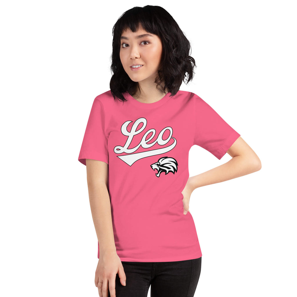 A woman modeling a bright pink short-sleeve t-shirt with a white 'Leo' script graphic and a black-and-white animal head logo on the front, set against a plain white background.