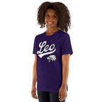 A woman with curly dark hair wearing a purple short-sleeve t-shirt with a white 'Leo' script and wildcat graphic on the front, photographed against a plain white background.