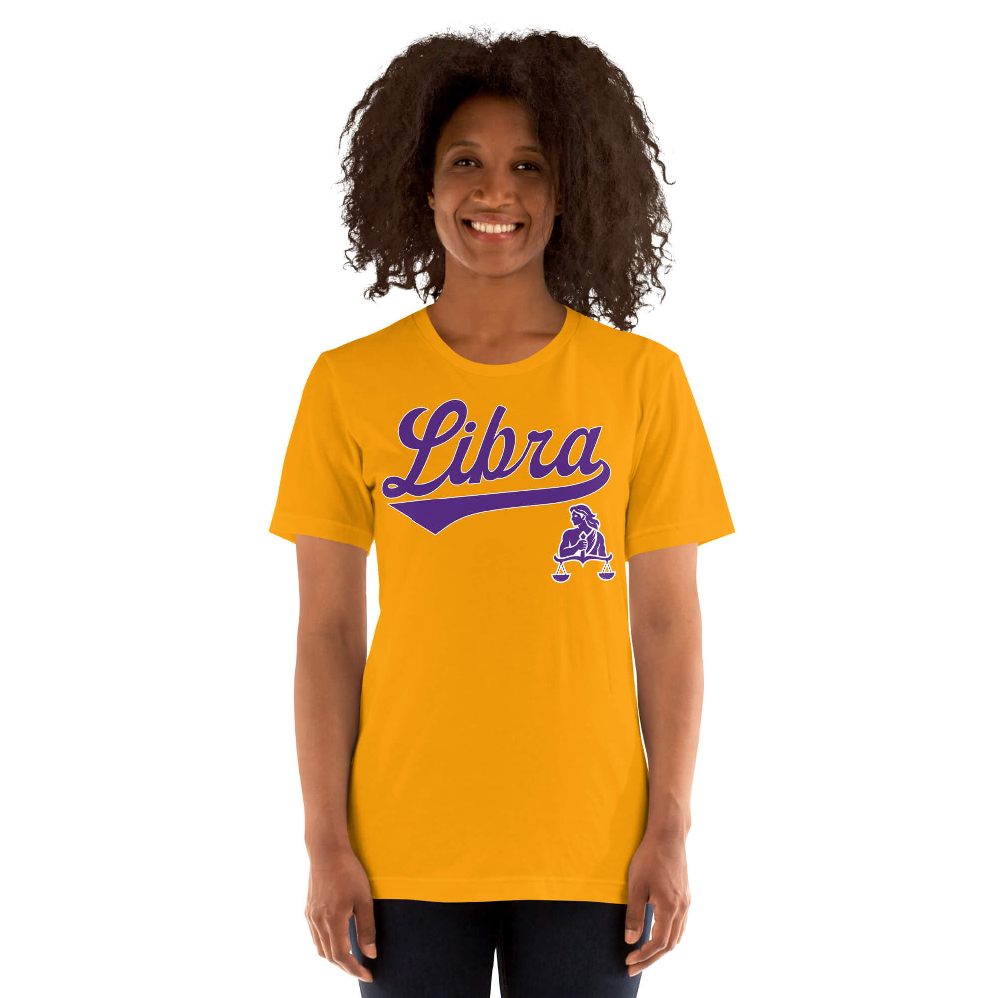 A smiling woman with curly dark hair wearing a bright gold t-shirt with a purple 'Libra' script and zodiac graphic, set against a plain white background.