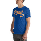 A man wearing a royal blue crewneck t-shirt with a vintage-style orange 'Pisces' graphic and a zodiac sign on the chest, set against a plain white background.