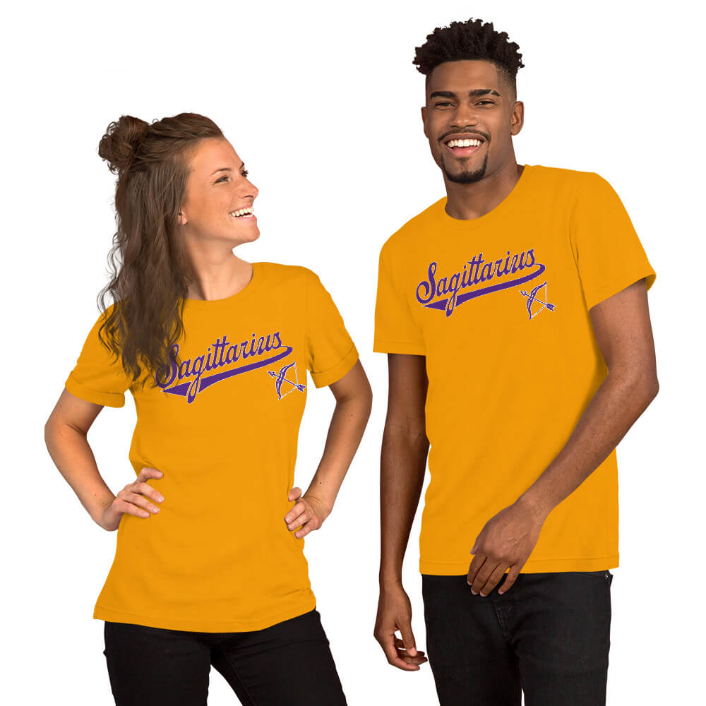A man and a woman modeling matching gold short-sleeve t-shirts with a purple 'Sagittarius' script and zodiac graphic on the chest, set against a plain white background.