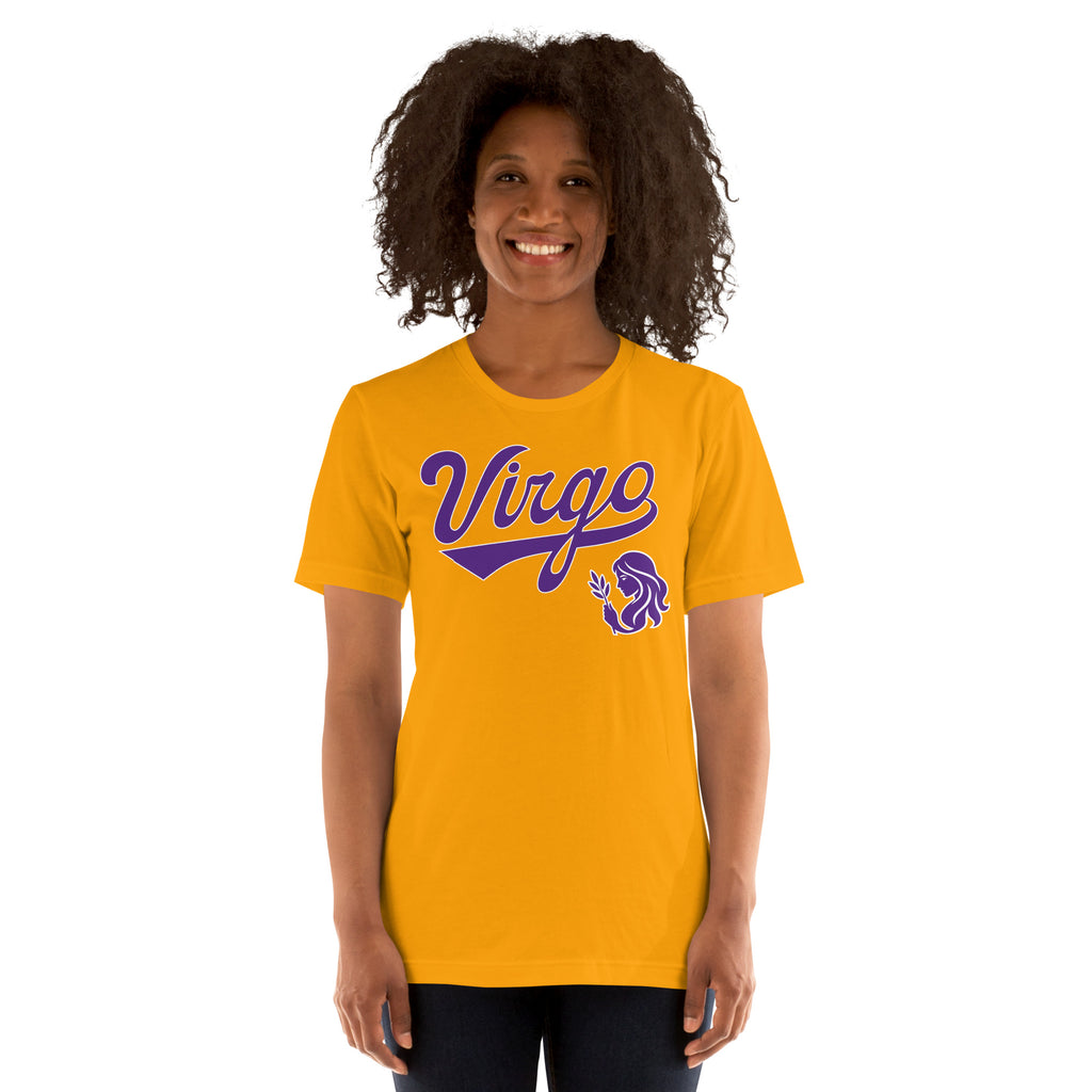 A smiling woman with curly dark hair wearing a bright yellow t-shirt with a purple 'Virgo' zodiac graphic on the chest, set against a plain white background.